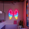 Three coloured Angel Wings LED neon sign installed on a white brick wall inside of a cafe.