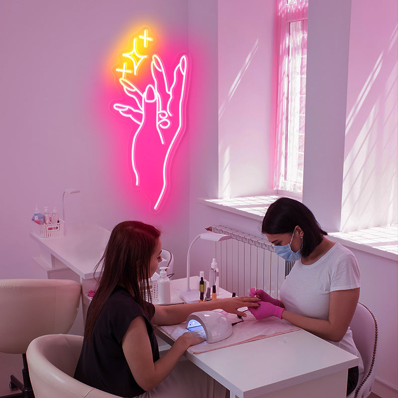 Nail Salon Pink and Yellow neon light. Hand showcasing beautiful nails accompanied by 3 sparkles.