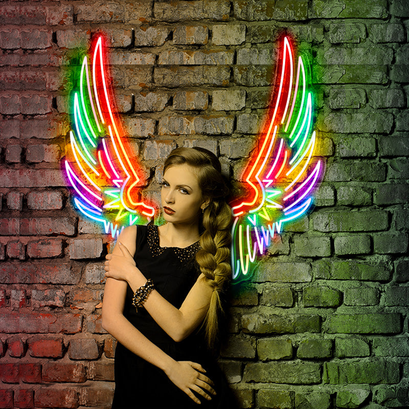 Edgy cool girl posing infront of a brick wall with a Rainbow Angel Wings LED Neon Sign installed onto it. 
