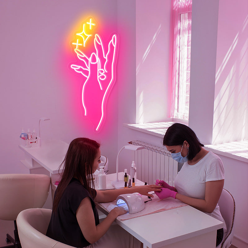 Nail Salon Pink and Yellow neon light. Hand showcasing beautiful nails accompanied by 3 sparkles. 
